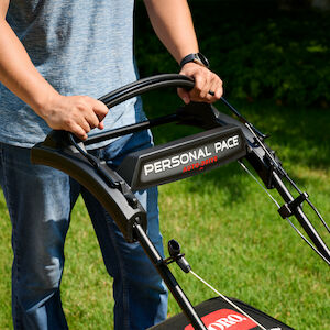 Man standing behind the Toro mower with his hands on the Personal Pace handle.