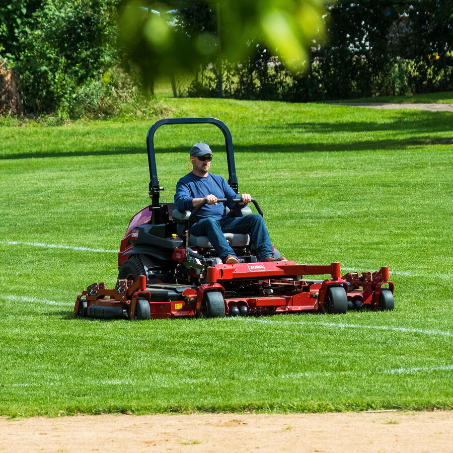 Man on a Toro Z Master 7500 series mower - mowing the outfield of a park baseball field. 