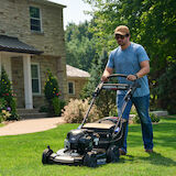 Image of man mowing the front lawn of a house with a Toro mower, model 21485.