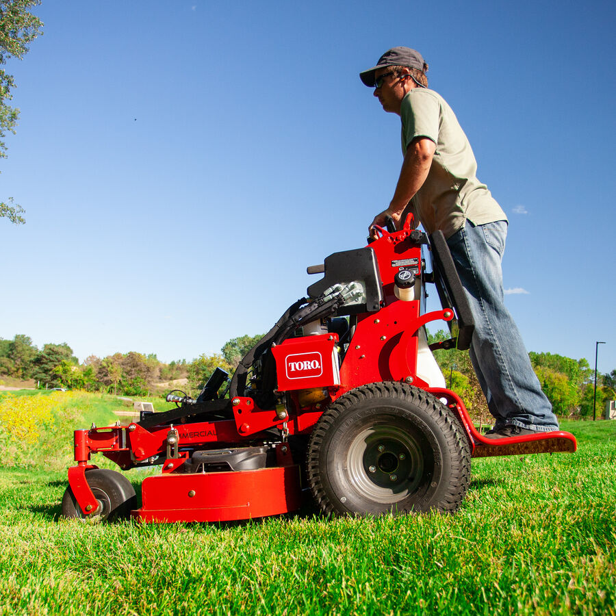 GrandStand® MULTI FORCE Stand-On Gas Mower in use - mowing down a slight incline