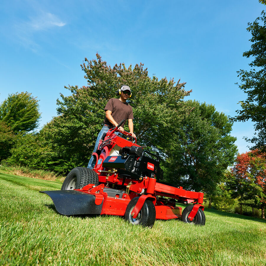 Man using a Toro GrandStand mower - mowing down an incline.