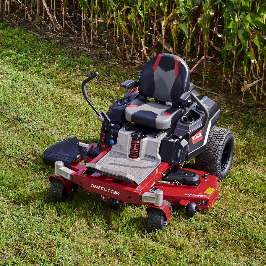 Mower on grass in front of corn field