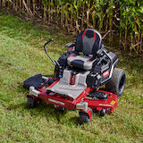 Mower on grass in front of corn field