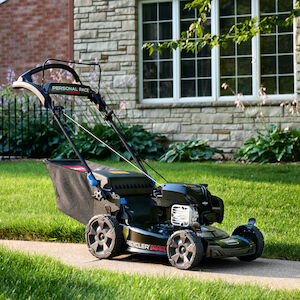 Toro mower, model 21485, on the sidewalk in front of lawn and house.