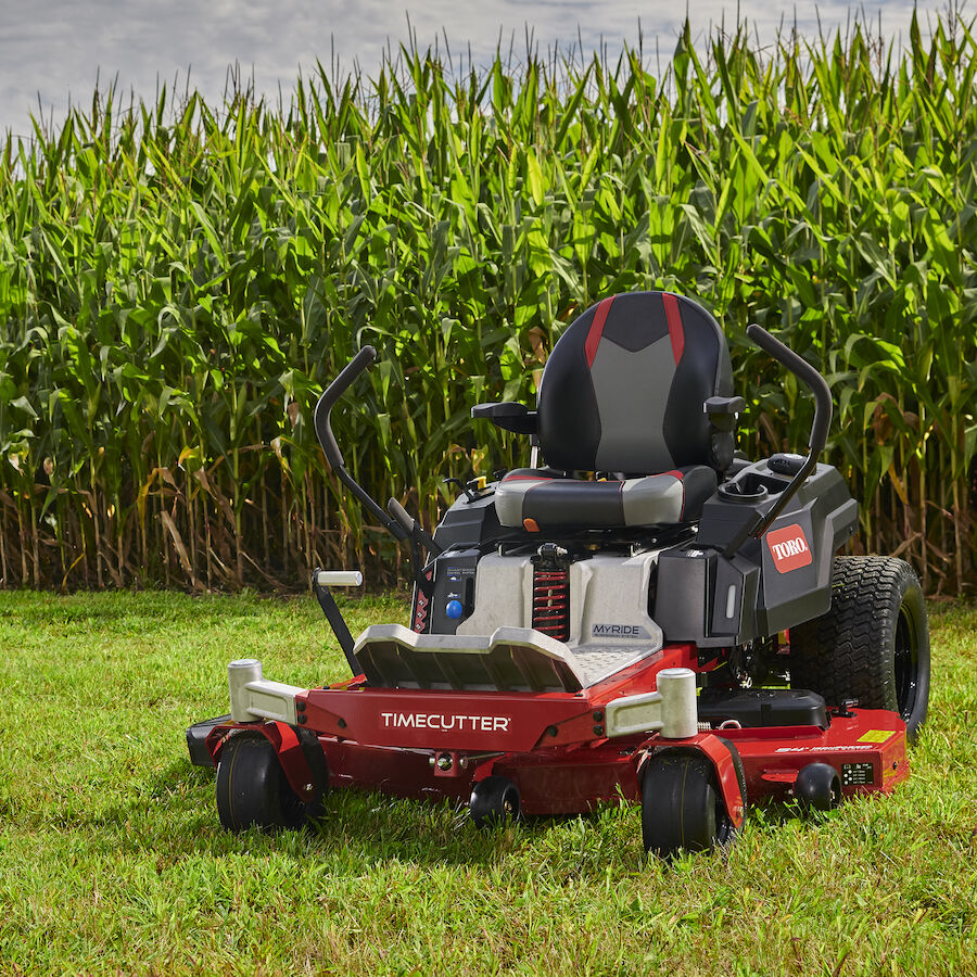 Mower on grass in front of corn field