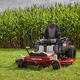 Mower on grass in front of corn field