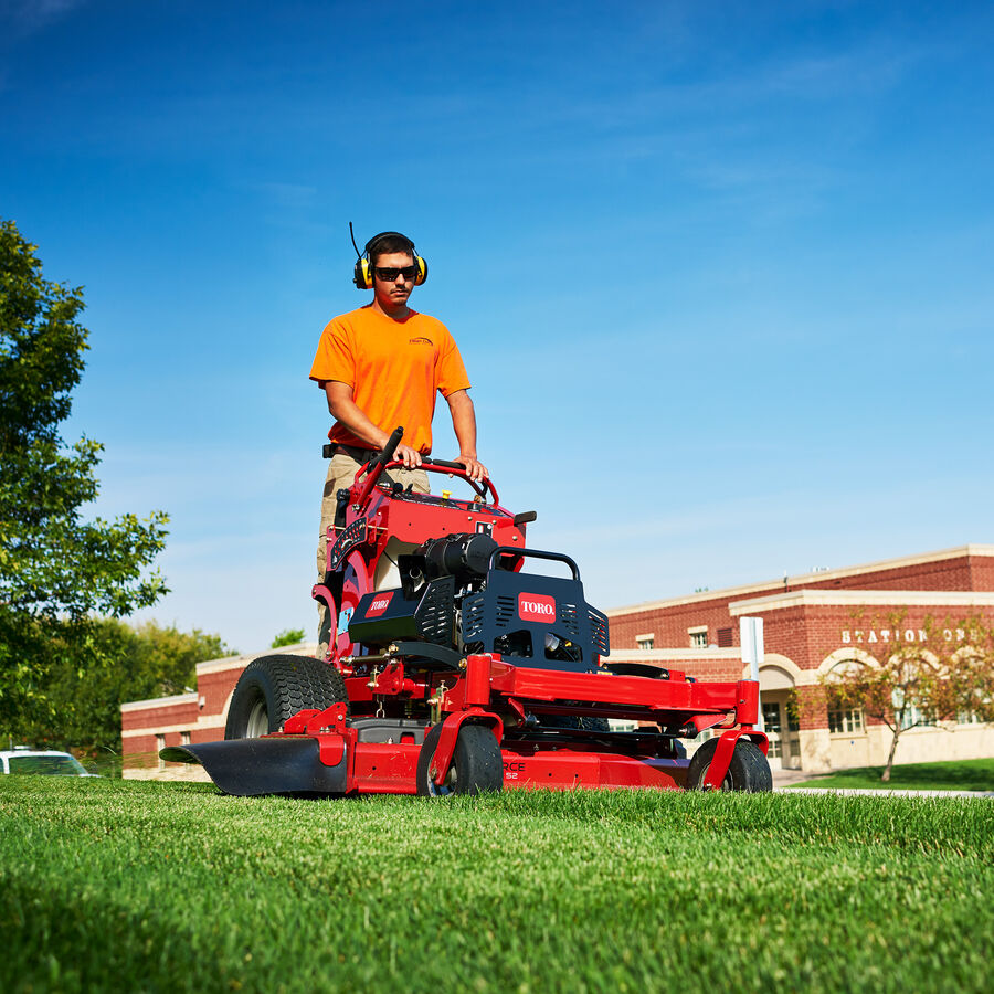Man using a Toro GrandStand mower mowing a property in front of a fire station