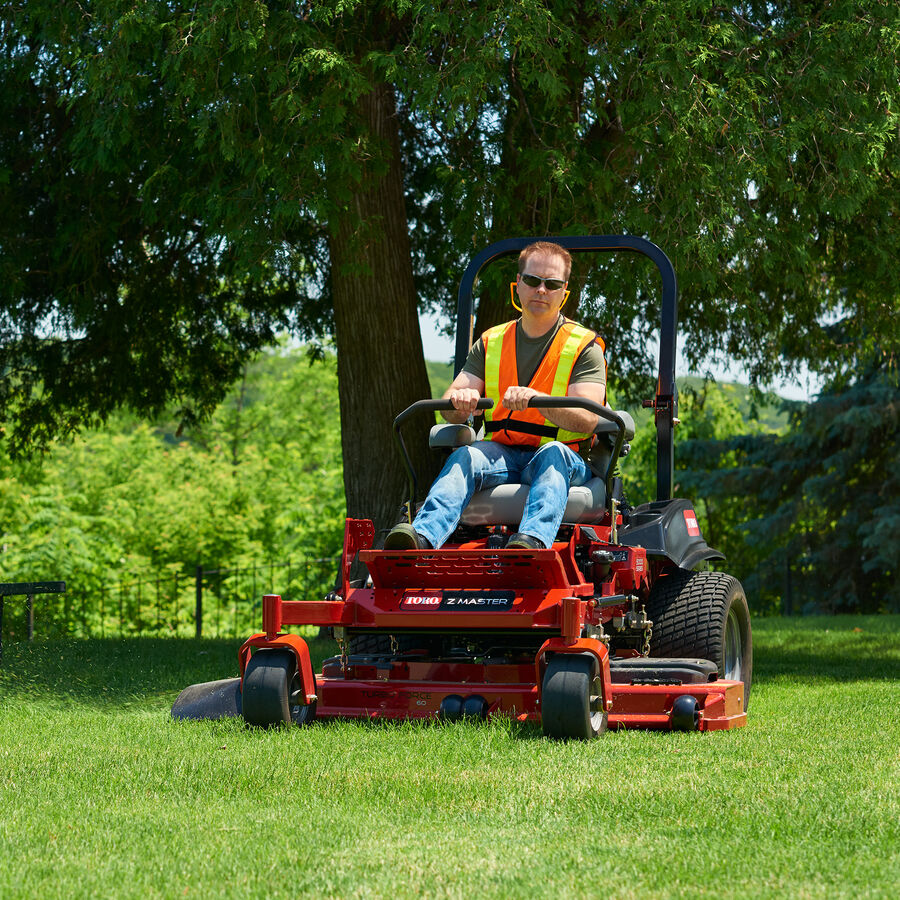 Man on a Z Master 5000 mower mowing a park with a tree in the background