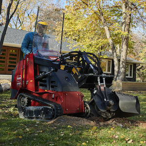 Dingo stump grinder attachment in front of house grinding a stump