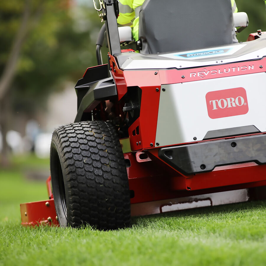 Z Master Revolution mower in use - close up of the rear of the mower showing the back left tire and rear cover with Toro logo shield on the cover.