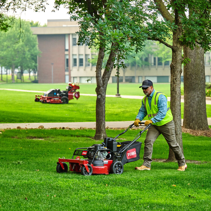 TurfMaster in use - man mowing by trees