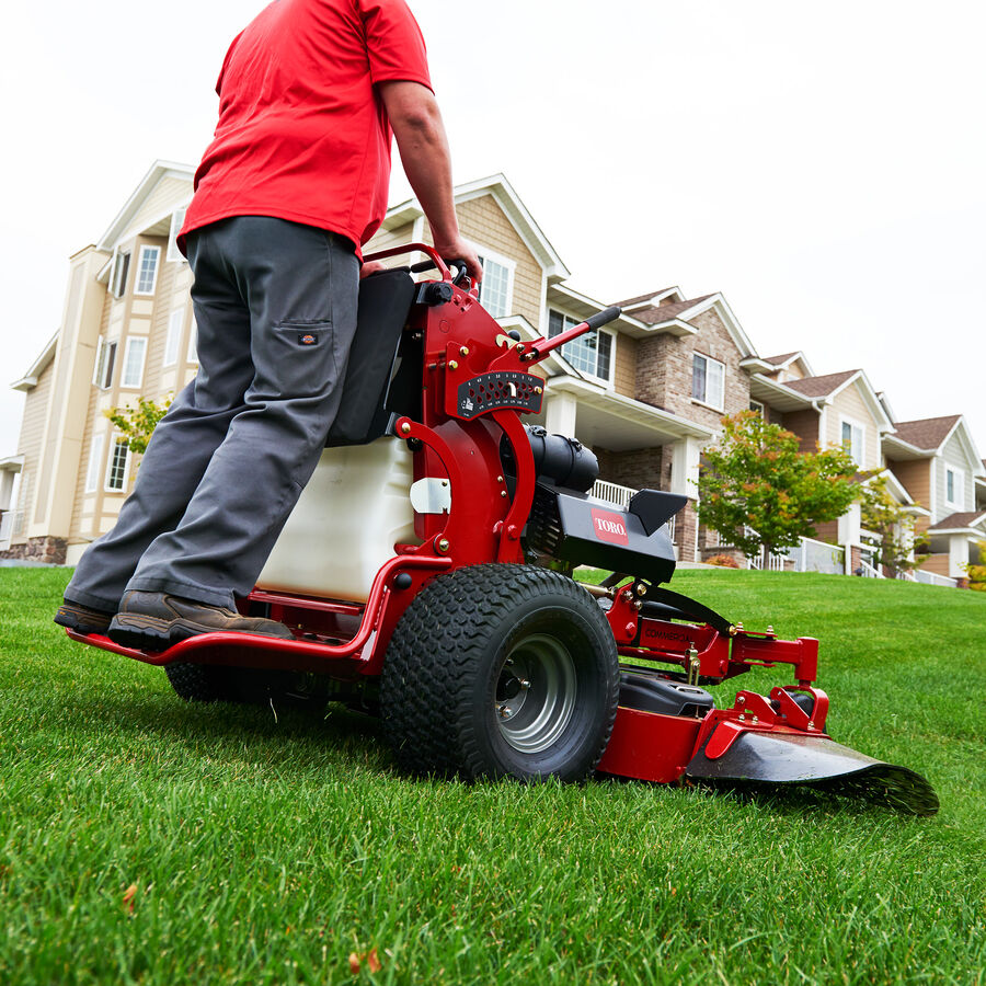 Person using a Toro GrandStand mower mowing in front of townhouse complext 