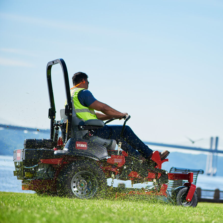 Man mowing the lawn with a Toro Z Master 6000 Series mower - close up showing the grass clippings getting dispersed back on the grass.